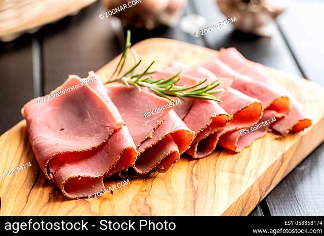 Sliced beef ham on cutting board on black table