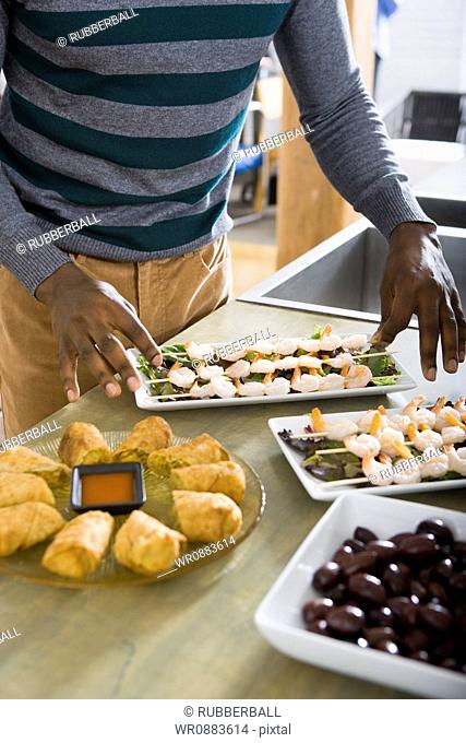 Mid section view of a man arranging appetizers on platters
