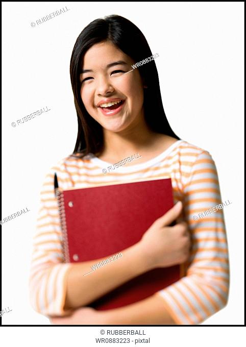 Close-up of a teenage girl holding a spiral notebook