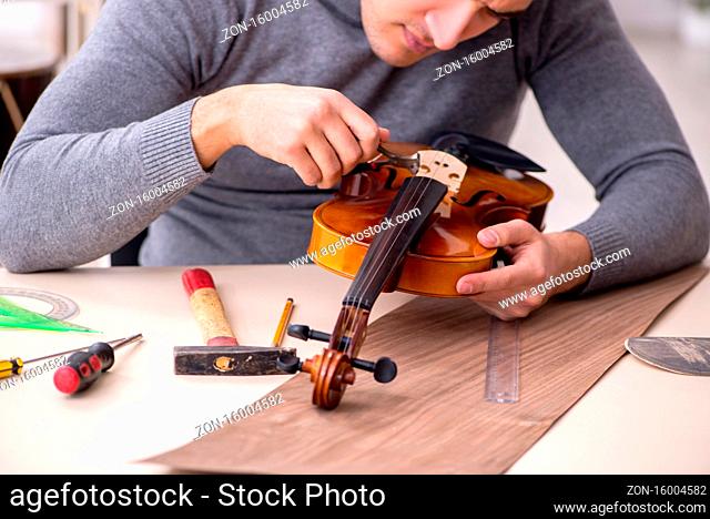 Young male repairman repairing violin in workshop