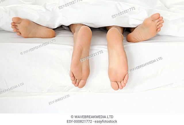 Close up of couples feet while hugging in their bed at home