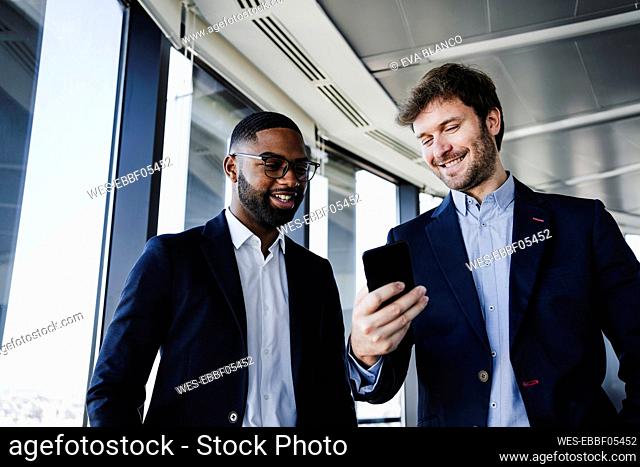 Happy businessmen sharing smart phone in coworking office