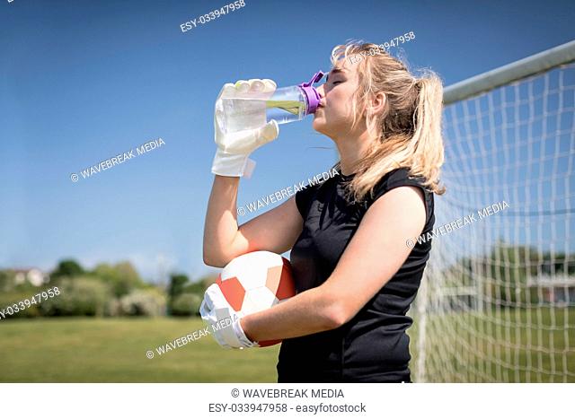 Thirsty soccer player drinking water on field