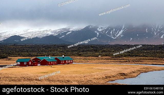 Wooden cottage houses near a small lake under the mountains covered in snow in Iceland