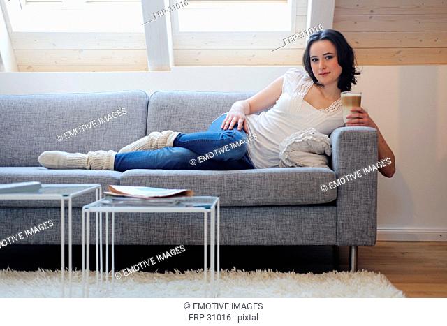 Young woman on couch drinking Latte Macchiato