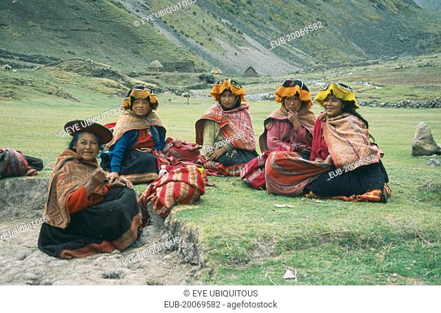 Local Quechuan women sat on grass, wearing traditional dress