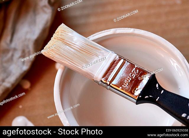 Brush soaked in white paint for painting walls