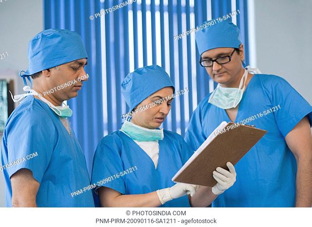 Three surgeons discussing a medical record, Gurgaon, Haryana, India