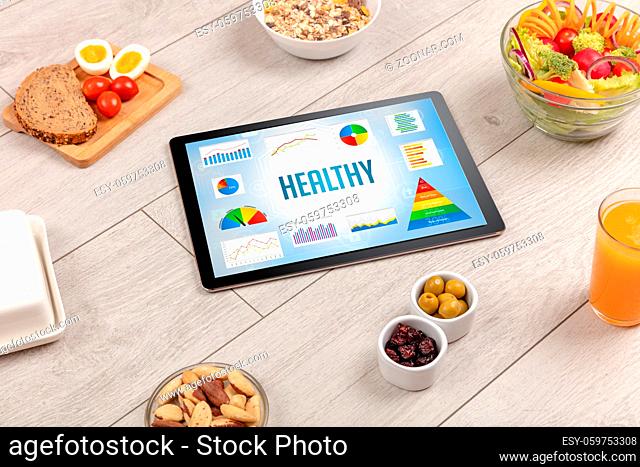 Organic food and tablet pc showing HEALTHY inscription, healthy nutrition composition