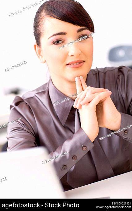 Young businesswoman thinking in her office, interlocking his hands
