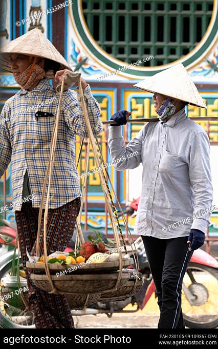 22 November 2022, Vietnam, Hoi An: Two women with cone hats carry baskets with fruit. Photo: Sebastian Kahnert/dpa. - Hoi An/Quang Nam/Vietnam