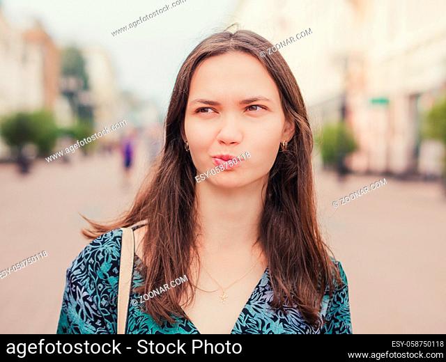 displeased handsome young woman with grimace looking away outdoors