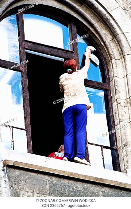 Eine Frau beim Fenster putzen. Gefahr beim putzen im Haushalt
