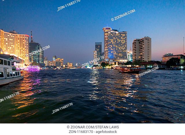 Skyline and boats at the pier for night cruise on the Chao Phraya river in Bangkok