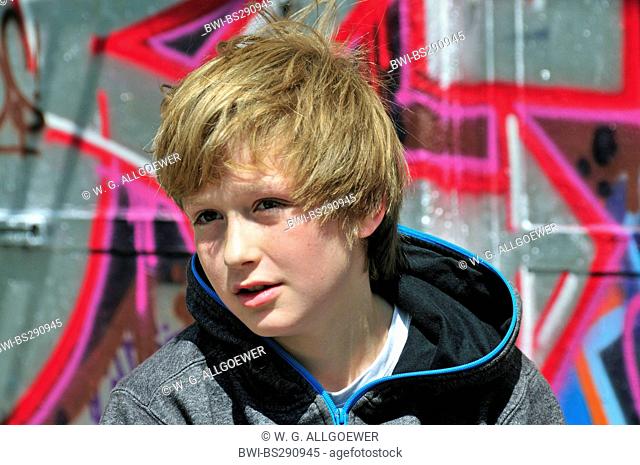 11 years old boy sitting in front of a graffiti wall