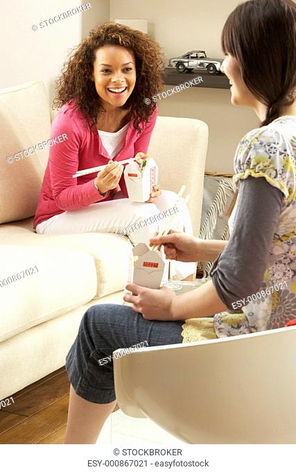 Two Female Friends Enjoying Chinese Takeaway Meal At Home