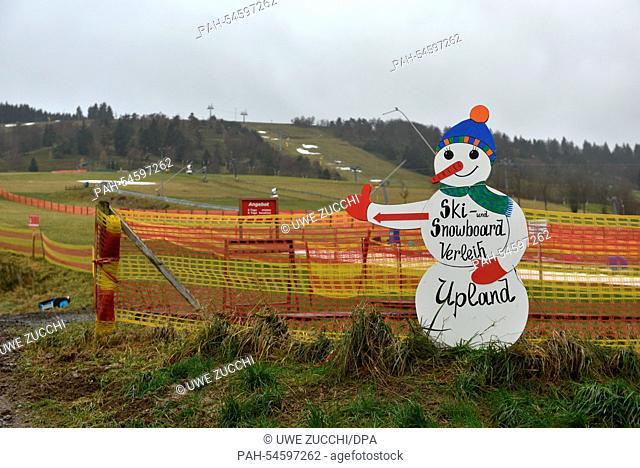 A snowman figure advertizes a ski and snowboard rental in front of green meadows in Willingen, Germany, 23 December 2014