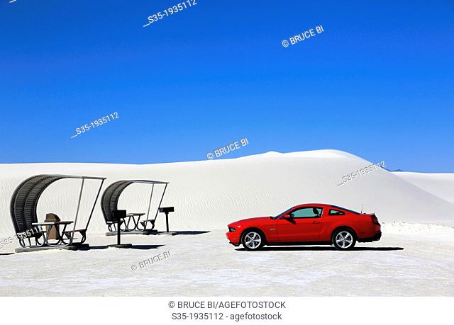 A red car with shaded picnic tables in the picnic area in White Sands National Monument. Alamogordo. New Mexico. USA