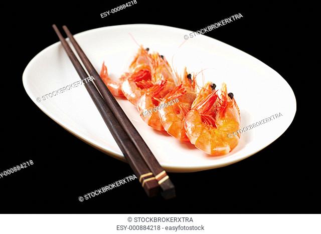Image of tasty shrimps lying in row with two chopsticks near by
