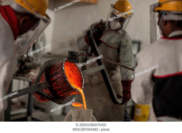 Workers casting metal in a foundry