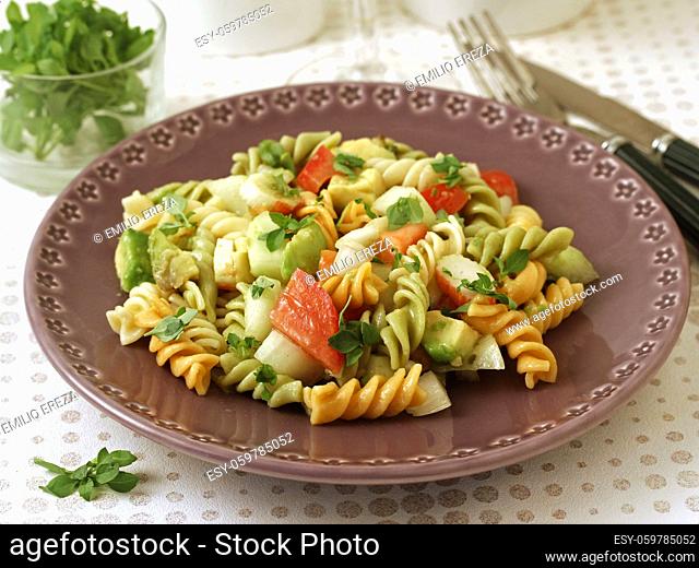 Salad of pasta. Spirals with vegetables, surimi and avocado. With leaves of basil as condiment