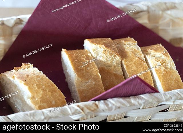 Baguette slices on basket wiyh purple napkin in restaurant