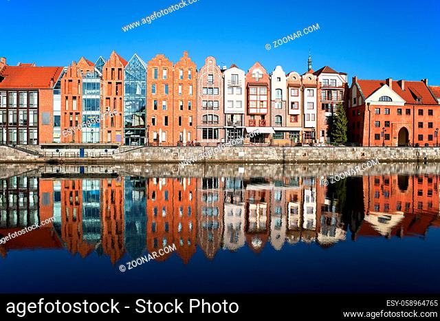 City of Gdansk, Poland, row of narrow houses at river waterfront with mirror reflection in the water