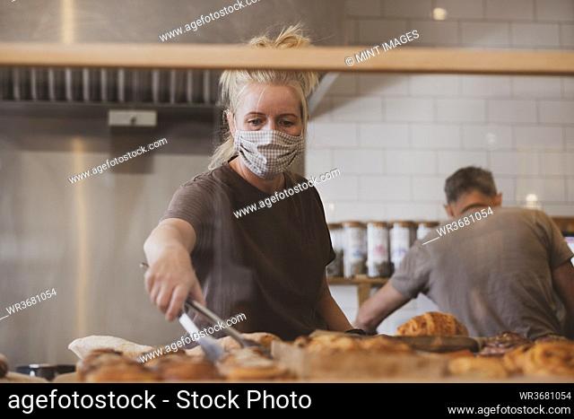 Blond waitress wearing face mask working in a cafe
