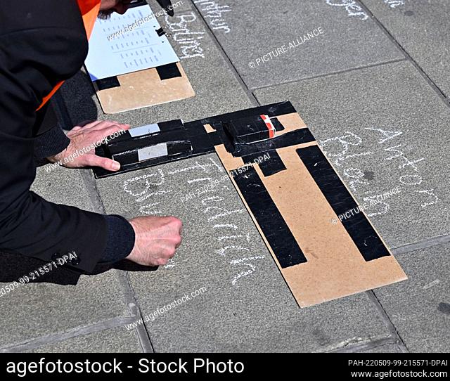 09 May 2022, Thuringia, Erfurt: A man writes names on Willy Brandt Square in front of the main train station during the ""Writing Against Forgetting"" campaign