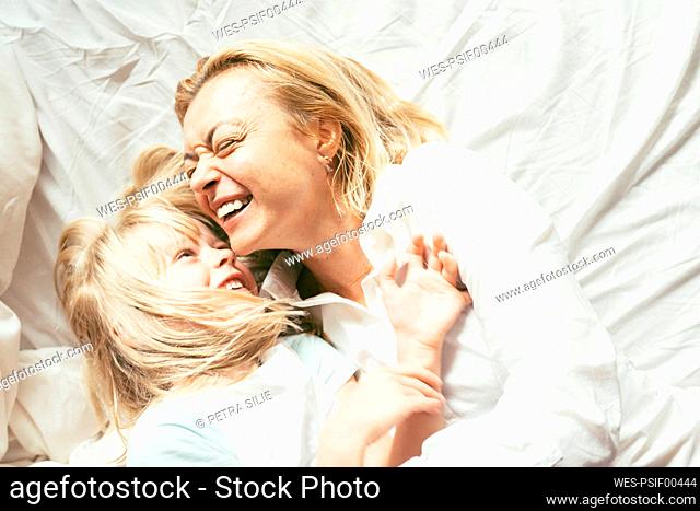Cheerful mother and daughter lying down in bedroom
