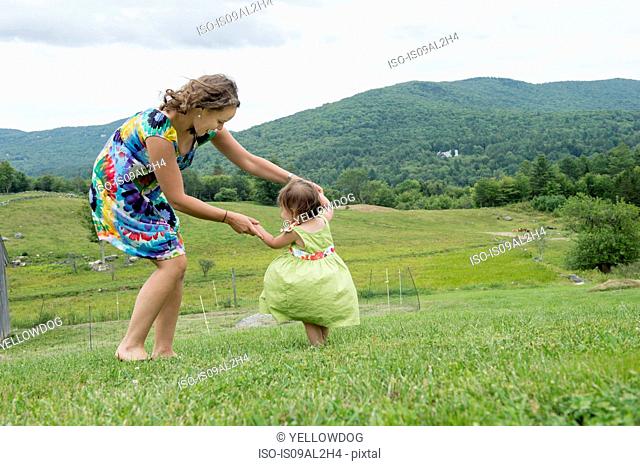 Mother and daughter dancing together in field