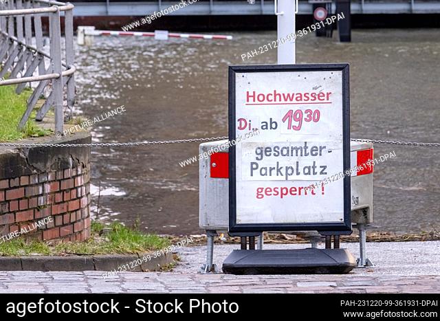 20 December 2023, Hamburg: The water of the Elbe floods a parking lot in Hamburg-Övelgönne. Flood warnings have been posted at the parking lot since Tuesday...
