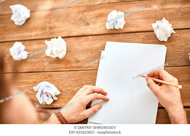 Young businessman hands with pencil over blank paper with crumpled sheets near by