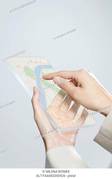 Woman using transparent digital tablet with touch screen to view map, cropped