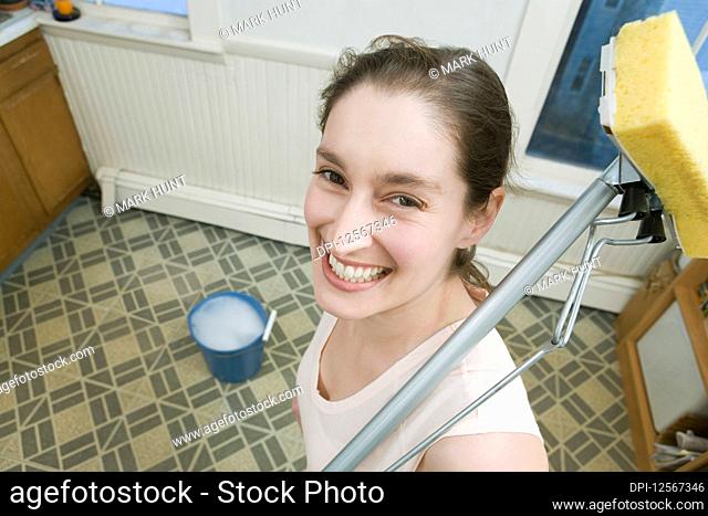 Portrait of a mid adult woman holding a mop and smiling