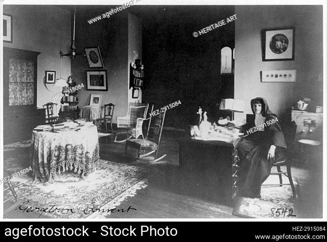 Georgetown Convent, Washington, D.C. - nun seated at desk in furnished room, not after 1892. Creator: Frances Benjamin Johnston