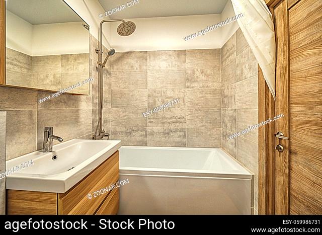 Bright clean Small beige tile bathroom with bath tube and sink