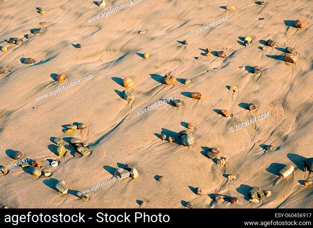 colorful stones in sand on beach - pebble stone background