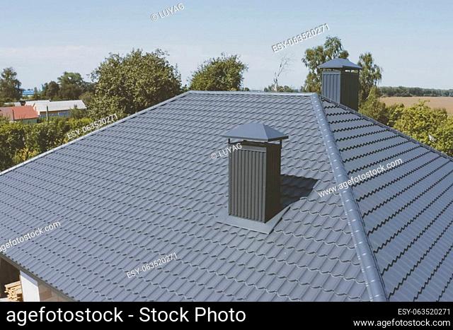 Modern roof made of metal. Gray-blue metal roof tiles on the roof of the house. Corrugated metal roof and metal roofing