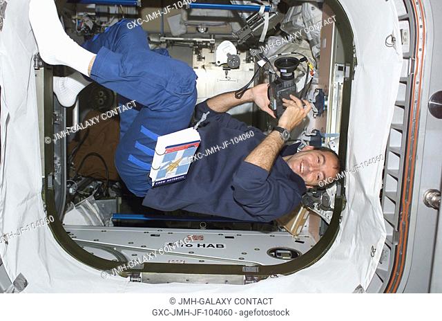 Astronaut Philippe Perrin, STS-111 mission specialist representing CNES the French Space Agency, holds a camera while floating in the hatch between the Unity...
