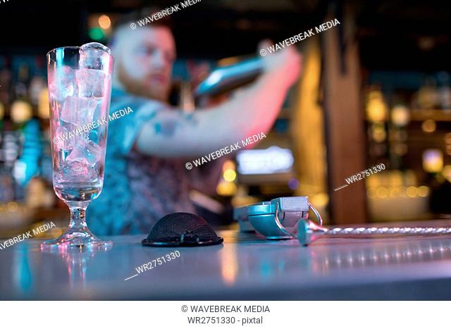 Bartender preparing a drink with bar accessories at counter