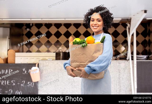 woman with foodstuff in paper bag over food truck