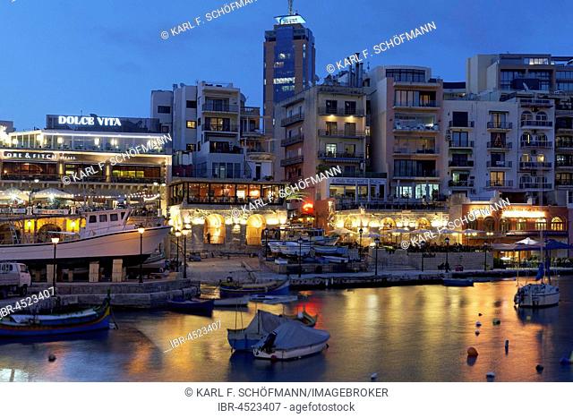 Spinola Bay with terrace taverns and Portomaso Tower, evening atmosphere, St. Julian's, Malta