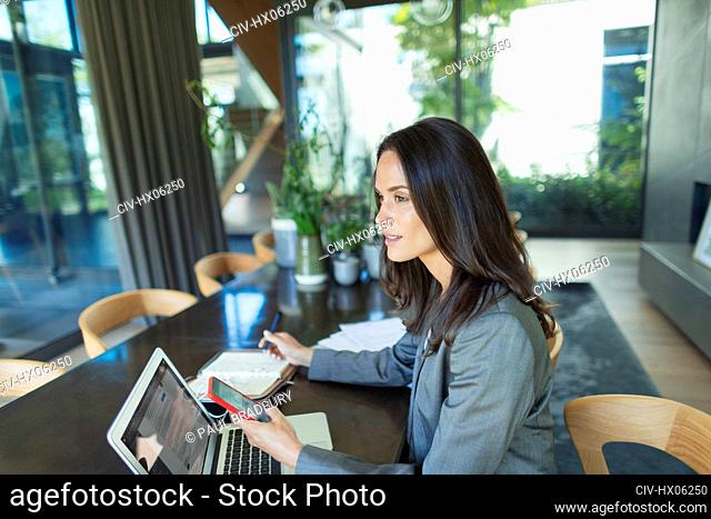 Businesswoman working from home, using smart phone and laptop
