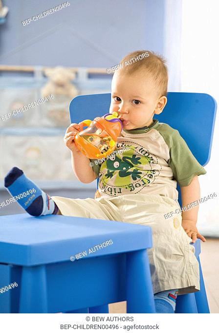 Baby boy drinking from an orange cup