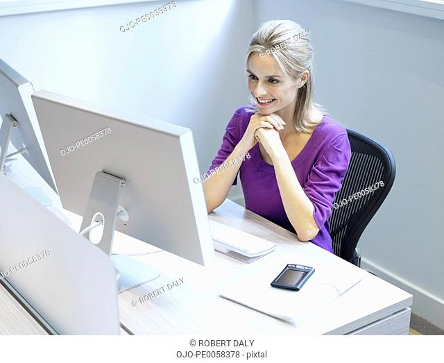 Businesswoman at her desk in an office smiling