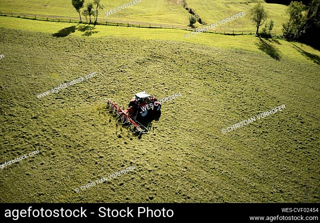 Man mowing land using tractor at sunny day