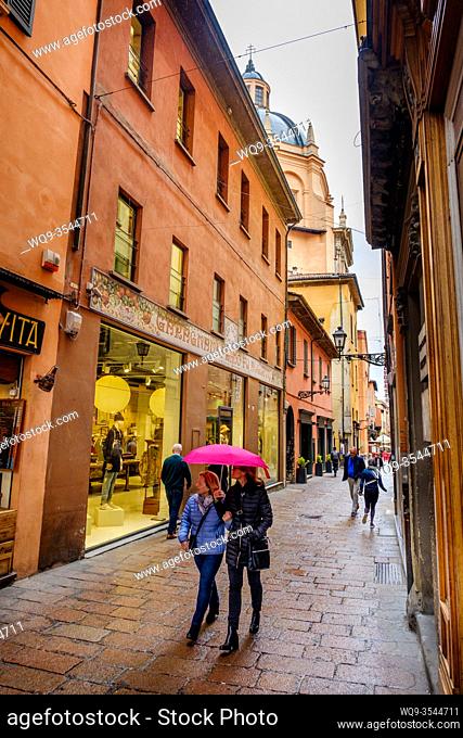 People walking in the rain in a side street near the Piazza Maggiore, Bologna, Italy