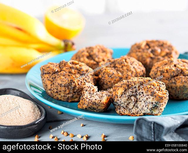 Close-up view of healthy gluten-free homemmade banana muffins with buckwheat flour. Vegan muffins with poppy seeds on blue plate over gray wooden table