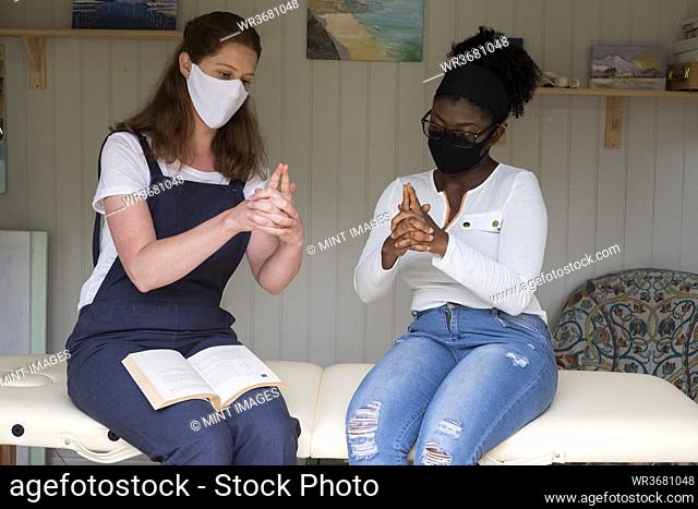 Woman and female therapist in face masks, hands steepled, EFT therapy